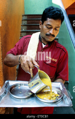 Cameriere versando sambar su idli in al ratna cafe ; Madras Chennai ; Tamil Nadu ; India n. MR Foto Stock