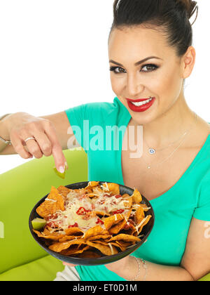 Giovane donna ispanica con un piatto di stile Messicano Nachos ricoperti in malto grattugiate il formaggio e una salsa piccante salsa isolata contro uno sfondo bianco Foto Stock