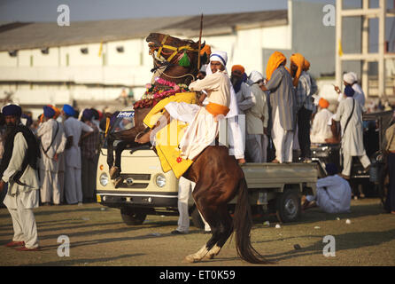 Nihang o guerriero Sikh sul suo cavallo prima di acrobazie perpetua Guru sikh Granth Sahib al Khalsa sportivo ; Nanded Foto Stock