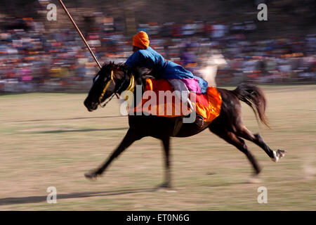 Nihang o guerriero Sikh che trasportano lancia eseguono acrobazie a cavallo durante la hola Mohalla festival di Anandpur sahib Foto Stock