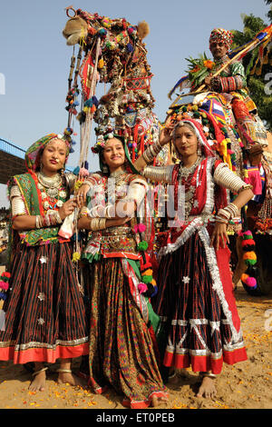 Ragazze in gioielli tradizionali e di costume di Rajasthani in piedi nella parte anteriore del cammello decorate in Pushkar fair ; Rajasthan Foto Stock