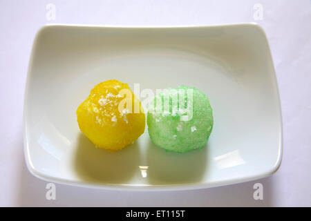 Mithai ; nariyal colorati ka laddoos nel rettangolo piastra su sfondo bianco Foto Stock