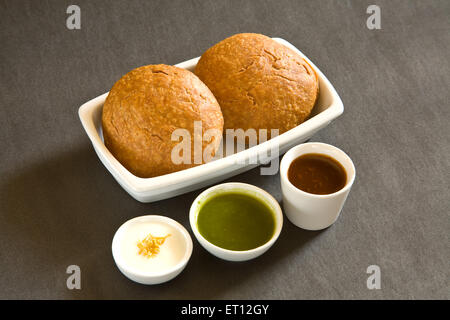 Indian snack fritti shahi khasta kachori chaat nella ciotola yogurt verde coriandolo e chutney di tamarindo sfondo nero Foto Stock