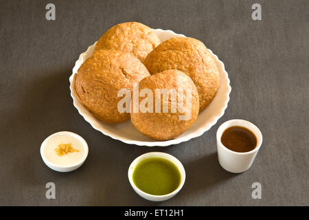 Indian snack fritti shahi khasta kachori chaat nella ciotola yogurt verde coriandolo e chutney di tamarindo sfondo nero Foto Stock