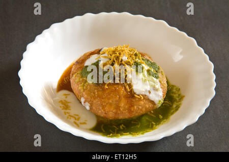 Indian snack fritti shahi khasta kachori chaat yogurt verde coriandolo e chutney di tamarindo sev servito in tazza sfondo nero Foto Stock