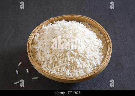 ; I grani di riso basmati oryza sativa nel recipiente di canna su sfondo grigio 20 Maggio 2010 Foto Stock