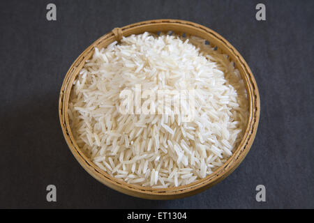 ; I grani di riso basmati oryza sativa nel recipiente di canna su sfondo grigio 20 Maggio 2010 Foto Stock