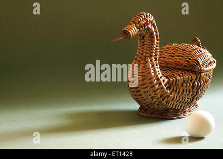 Artistico cestello di canna forma di anatra con uovo solo su sfondo verde Foto Stock