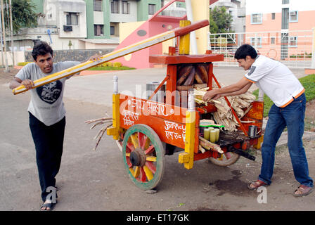 Uomo indiano venditore usando il manuale di succo di canna da zucchero macchina estrattore Nasik Maharashtra India Signor#364 Foto Stock