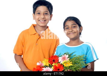 Fratello e Sorella di contenimento bouquet di fiori e festeggia il compleanno ; Mumbai Bombay ; Maharashtra ; India Signor#152 Foto Stock