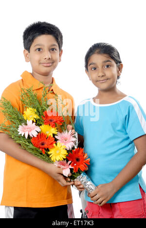 Fratello e Sorella di contenimento bouquet di fiori e festeggia il compleanno ; Mumbai Bombay ; Maharashtra ; India Signor#152 Foto Stock