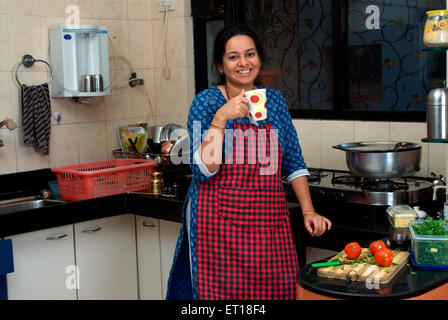 Donna con grembiule in cucina a bere caffè India Signor#364 Foto Stock