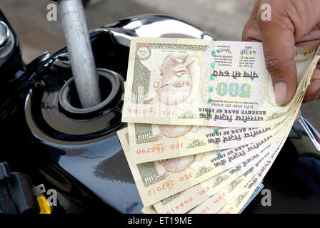 La mano che mostra la valuta indiana del cinquecento rupie pagando per la benzina in moto il signor#364 Foto Stock