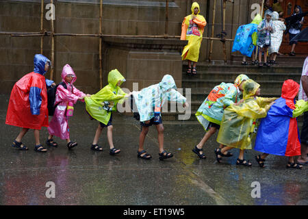 Bambini delle scuole che indossano impermeabili colorati in linea con Mumbai Maharashtra India bambini indiani sotto la pioggia Foto Stock