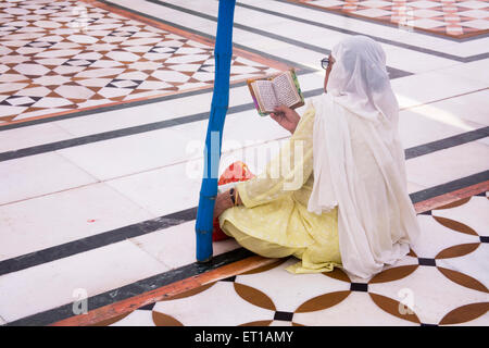 La religione sikh donna orante seduto sulla struttura floreale pattern del marmo bianco all'interno Swarn Mandir tempio dorato ; Amritsar Foto Stock