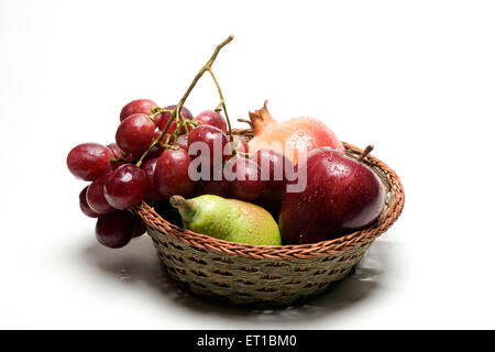 Frutti ; acqua scende su apple ; melograno ; pera e uva nel paniere di legno su sfondo bianco Foto Stock