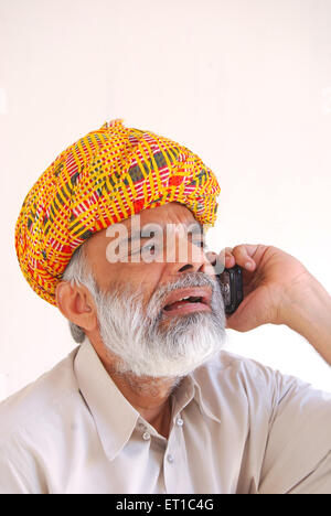 Uomo di Rajasthani in turbante parlando al telefono cellulare ; Jodhpur ; Rajasthan ; India Signor#704 Foto Stock