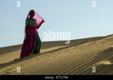 Donna che cammina su Sam Dune di sabbia del deserto di Thar Jaisalmer Rajasthan India Asia MR # 704 Foto Stock