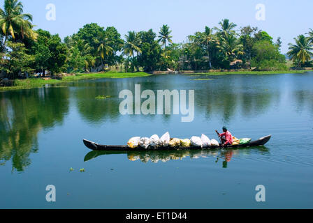 Uomo che porta i sacchi di grandi dimensioni in barca nel fiume ashtamudi ; Quilon ; Alleppey ; Kerala ; India Foto Stock