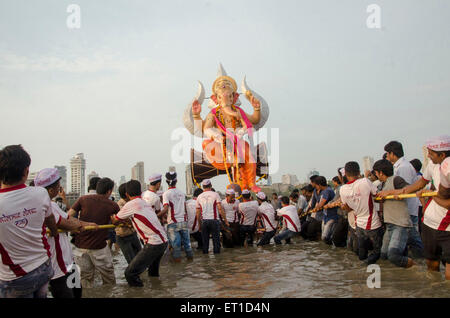 Volontari trascinando un enorme idolo di Ganpati per immersione in mare a Girgaon Chowpatty Mumbai India Asia Foto Stock