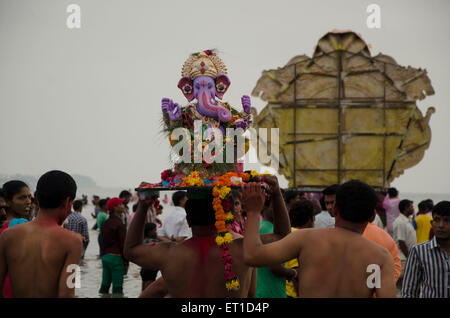 Persone che trasportano idolo di Ganpati per immersione in mare a Girgaon Chowpatty Mumbai India Asia Foto Stock