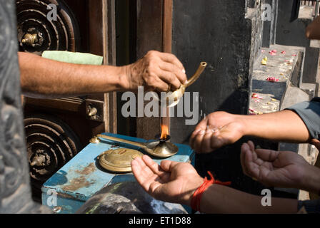 Sacerdote versando charnaamrita sulle mani di devoti ; Trivandram ; Kerala ; India Foto Stock