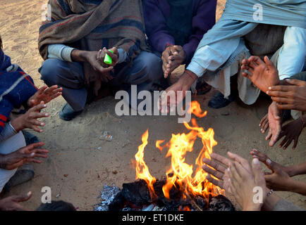 Gli abitanti di un villaggio di riscaldamento seduti intorno al fuoco Bikaner Rajasthan India Asia Foto Stock