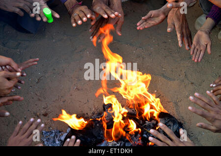 Popolazione rurale indiana abitanti del villaggio che si riscaldano seduti intorno al fuoco in inverno freddo ; Bikaner ; Rajasthan ; India ; Asia Foto Stock