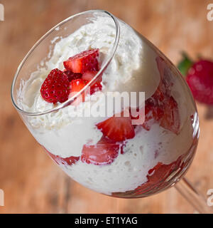 Vetro con panna montata e fragole in piccoli pezzi Foto Stock
