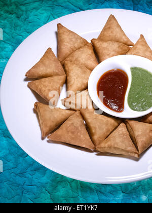 Il fast food ; samosa cocktail serviti nel piatto con data e chutney di coriandolo Foto Stock