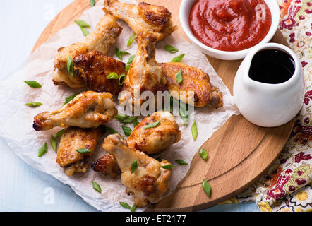 Alette di pollo fritte con salse sulla tavola di legno, vicino il fuoco selettivo, vista dall'alto Foto Stock