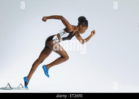 Atleta femminile lasciando il blocco di avviamento Foto Stock