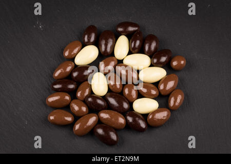 Mandorle in bianco, scuro, il cioccolato al latte sul bordo di pietra Foto Stock