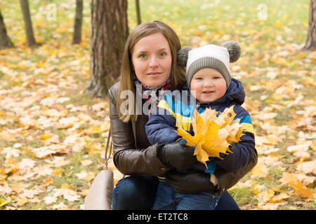 Madre e figlio giocare con le foglie in autunno park Foto Stock