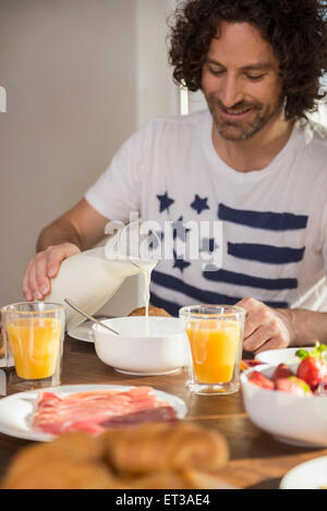 Metà uomo adulto avente la prima colazione al tavolo da pranzo, Monaco di Baviera, Germania Foto Stock
