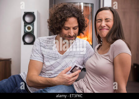 Metà uomo adulto che mostra il telefono cellulare a sua moglie, Monaco di Baviera, Germania Foto Stock