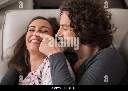 Metà adulto giovane sdraiato sul divano e sorridente, Monaco di Baviera, Germania Foto Stock