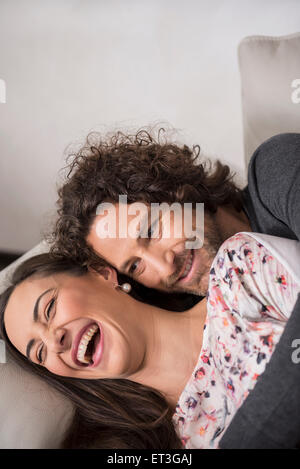 Metà adulto giovane sdraiato sul divano e sorridente, Monaco di Baviera, Germania Foto Stock