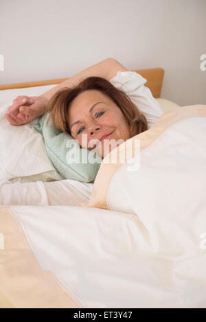 Senior donna che dorme sul letto nella sua camera da letto a casa di Monaco di Baviera, Germania Foto Stock