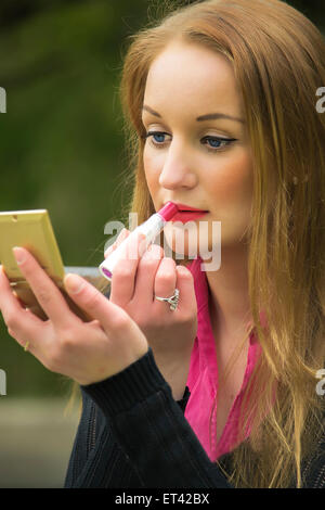 Piuttosto giovane donna mettendo su alcuni rossetto. Foto Stock
