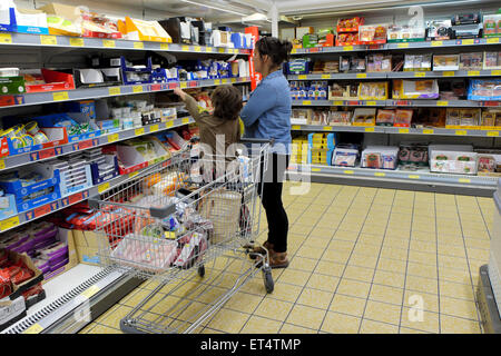 Madre donna bambino con carrello della spesa che sta cercando di scegliere i prodotti caseari al supermercato Aldi per la refrigerazione dello yogurt al formaggio Regno Unito KATHY DEWITT Foto Stock