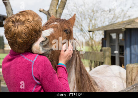 Donna che abbraccia il cavallo in stabile di Baviera Germania Foto Stock