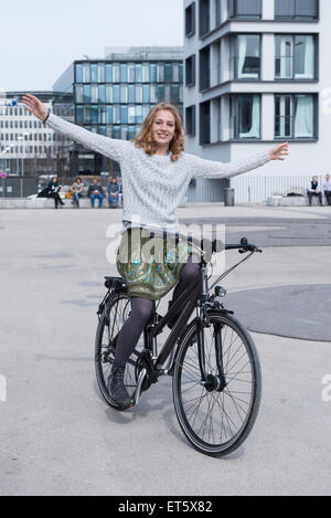 Giovane donna eseguendo stunt sulla bicicletta, Monaco di Baviera, Germania Foto Stock