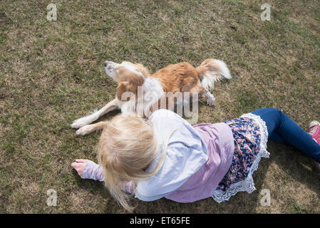 Ragazza adolescente che giace in posizione di parcheggio con il suo cane, Monaco di Baviera, Germania Foto Stock