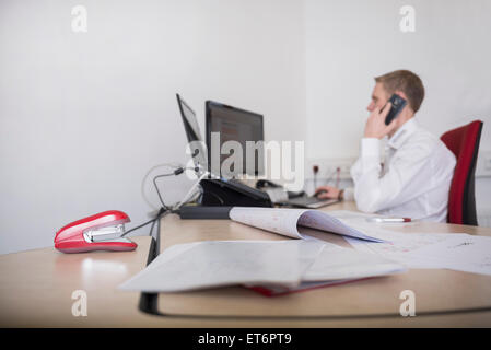 Uomo che lavora in ufficio e parlando al telefono cellulare, Monaco di Baviera, Germania Foto Stock