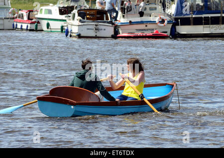 Un paio di divertirsi in una barca a remi sul Fiume Tamigi mentre in background, le persone stanno godendo del loro motore di incrociatori. Foto Stock