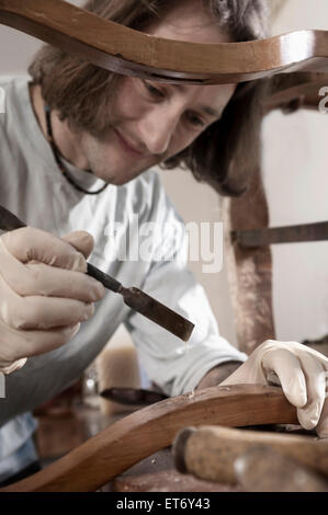 Carpenter applicare colla su antiche sedia in legno in officina, Baviera, Germania Foto Stock