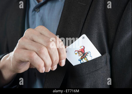 L'uomo mettendo joker carta da gioco sul suo Pocket, Baviera, Germania Foto Stock