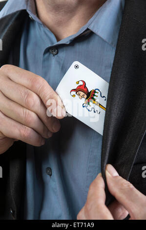 L'uomo mettendo joker carta da gioco sul suo Pocket, Baviera, Germania Foto Stock