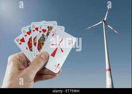 Turbina eolica con una mano d'uomo tenendo le carte da gioco in primo piano, Baviera, Germania Foto Stock